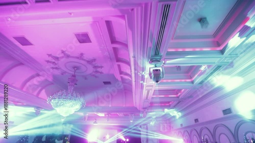 Camera Enters a Grand Banquet Hall with Stage, Spotlight Beams and Crowd Preparing for a Live Performance