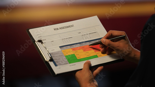 Detailed closeup hand holds clipboard analyzing operational risk assessment matrix chart to ensure safety and security focused workplace