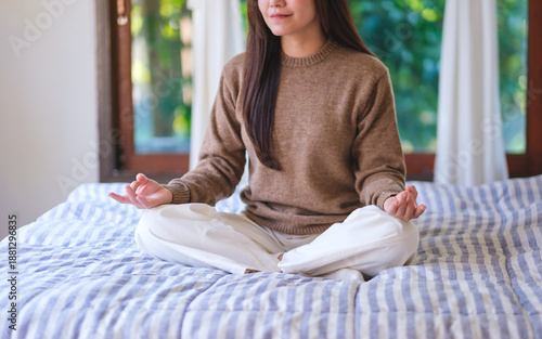 Wallpaper Mural Closeup image of a young woman meditating or practicing yoga in lotus pose on the bed Torontodigital.ca