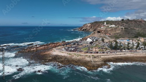 Sunny aerial circles rocky ocean point lighthouse at Mossel Bay, RSA