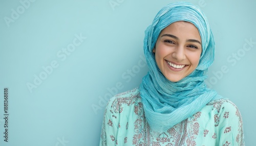 Wallpaper Mural Young woman wearing a bright blue headscarf smiles warmly against a solid light blue background Torontodigital.ca