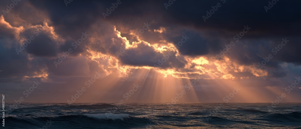 Naklejka premium Dramatic sunset with sunbeams over stormy ocean