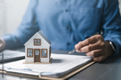 Foto Mortgage and real estate finance concept showing house model on documents with professional signing, representing home loan calculation, property investment, interest rates, and financial planning