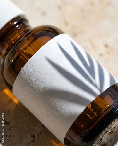 Macro close up of blank white paper label on amber glass cosmetic bottle. Textured product packaging mockup with palm leaf shadow.