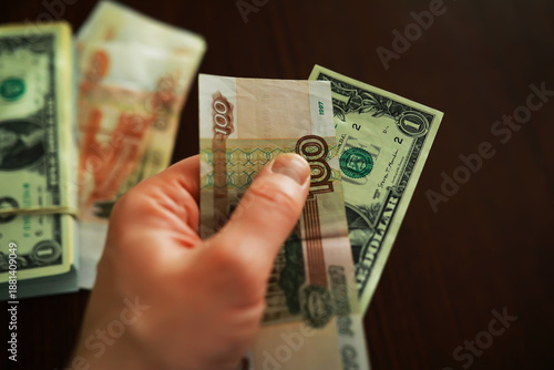 Close-Up of a Hand Holding Mixed Currency Notes Indoors on a Wooden Table