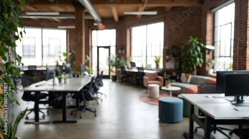 Soft focus view of a modern coworking office space with desks, chairs, plants, and couches