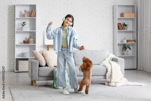 Fotografija Teenage girl in headphones with cute Toy Poodle dog dancing at home