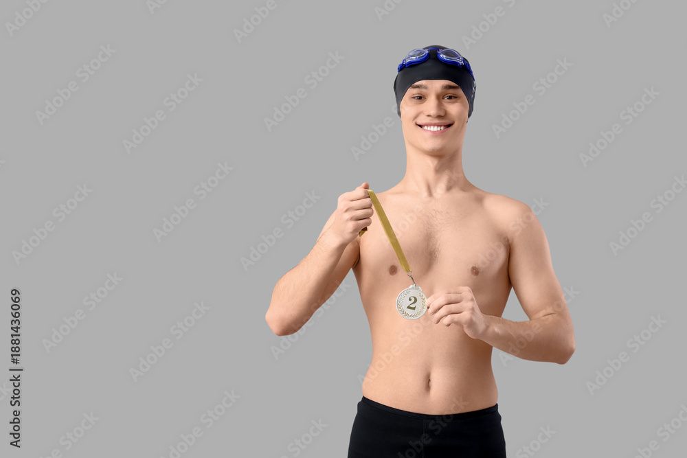 Obraz premium Young male swimmer with second place medal on light background