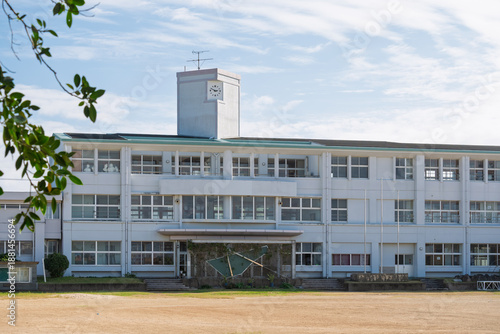 夏の青空と日本の田舎にある白い校舎の風景（アニメ風背景素材・コピースペース）

