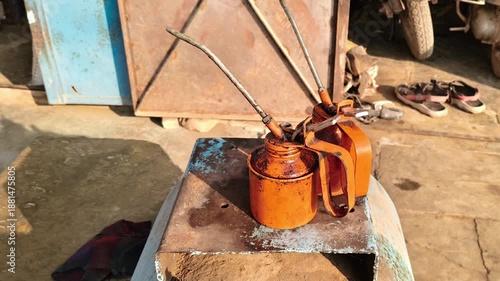 Pair of vintage manual oil pump cans on a rusty compressor tank