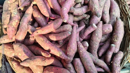 Fresh raw sweet potatoes in a wicker basket at a local market