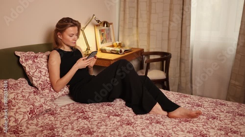 Woman relaxing on bed while using smartphone in room