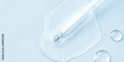 Drop of cosmetics and a pipette on a blue background. A product for skin, face or hair care. © Anna