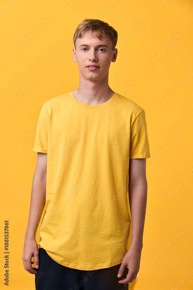 Fototapeta premium Young man wearing a yellow T shirt in a bright studio, casual fashion and relaxed pose, clean background, ideal for lifestyle or apparel showcase