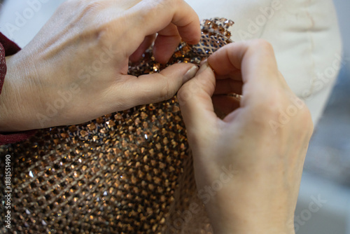 Photography A tailor is sewing an evening gown from special gold-colored fabric embellished with stones