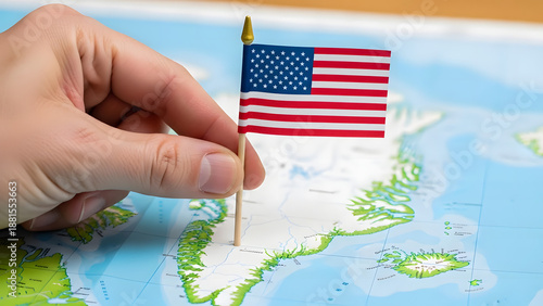 hand planting a small American flag on a map of Greenland
