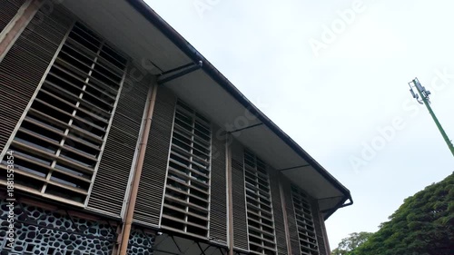Building Exterior with Louvered Windows and Antenna on Hillside.