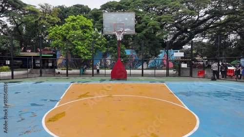 Outdoor Basketball Court - Empty Blue Court with Trees and Urban Setting.