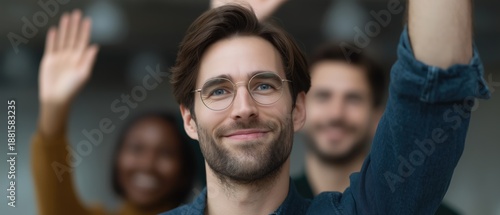 Wallpaper Mural Young man with glasses smiling and raising hand in casual group setting indoors Torontodigital.ca