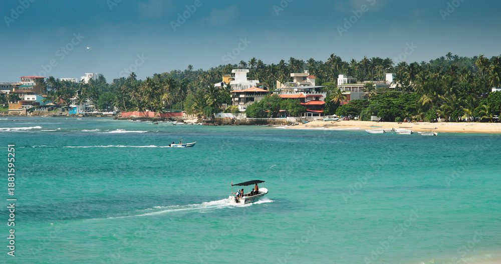 Obraz premium Dynamic Coastal View with Boats and Lush Greenery Nearby
