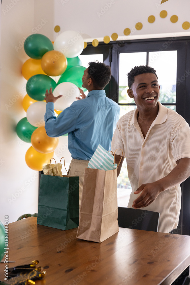 Obraz premium Diverse male friends decorating green gold balloons, arranging gift bags at home, copy space