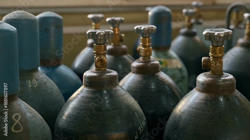 Industrial gas cylinders with valves stored in manufacturing facility. Gas supply, industrial storage and safety concept.