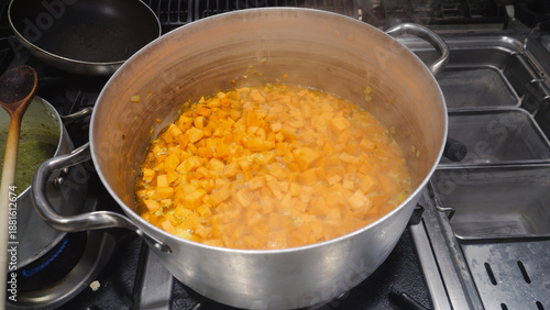 фотографія Sweet potato cubes are simmering in a large aluminum pot on a commercial gas sto