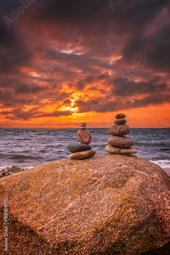 A small pebble tower on the seashore. A view of an empty coastline at sunset. A place for relaxation, meditation, and rest away from the city.