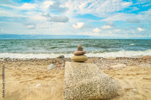 A small pebble tower on the seashore. A view of the empty coastline on a summer day. A place for relaxation, meditation, and rest away from the city.