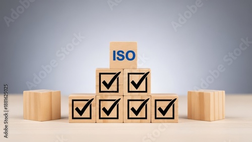 Wooden blocks with checkmarks and iso on top symbolizing quality control and certification process in a business or industrial setting with a grey background