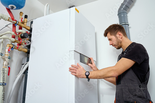 Foto Technician installing indoor heat pump system with pipes and expansion tank