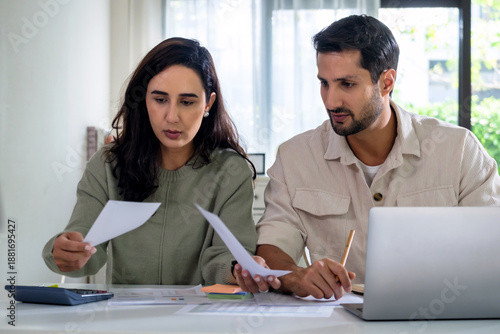 Couple personal finance and tax preparation at home as they review income tax documents with a calculator, supporting financial planning and household budget decisions