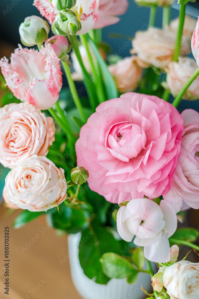 Obraz premium Beautiful bouquet of pink ranunculus and roses in a vase on a wooden table for romantic spring home interior or wedding celebration gift concept