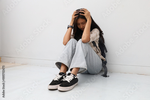 An Asian woman wearing casual clothes, sitting hunched over on the floor.