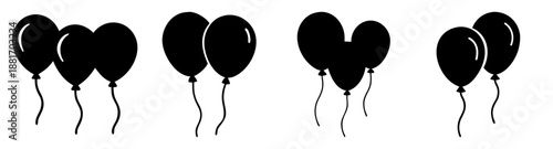 A group of black balloons floating in the air with ribbons trailing down