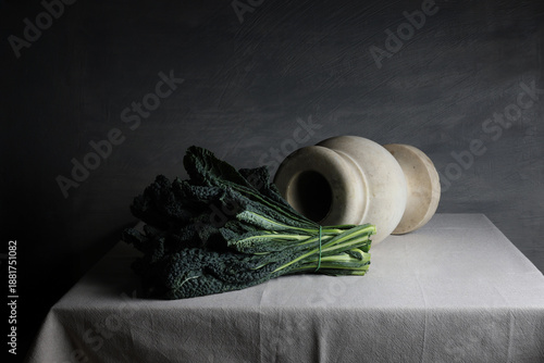 Cavolo nero e vaso in marmo bianco su tavolo in lino, composizione sobria ed essenziale