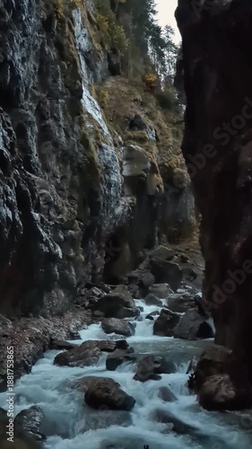 A dynamic slow motion video showing turquoise mountain water with white foam rushing between high rocky cliffs.