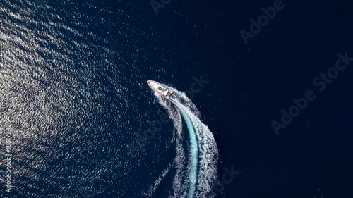 Overhead tracking view of a RIB motorboat driving in circles with speed over blue ocean