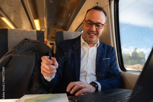 Smiling businessman traveling on train using laptop