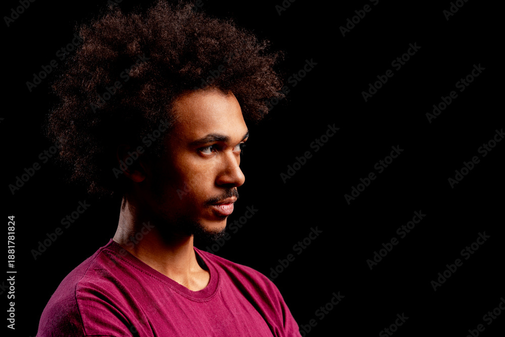 Obraz premium Young man with afro looking in contemplation, isolated on a black background