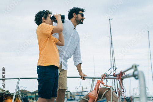 Father and son looking through binoculars on a boat, curiosity and exploration