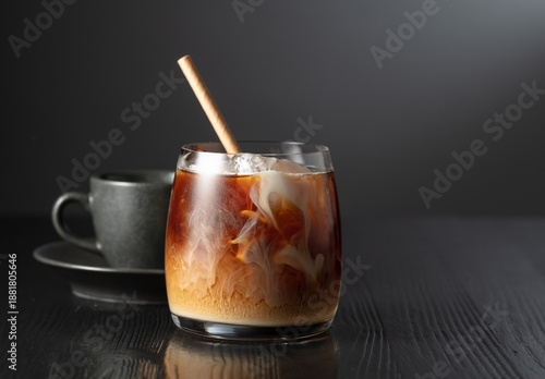 Iced coffee with cream and cup of black coffee on a black wooden table.