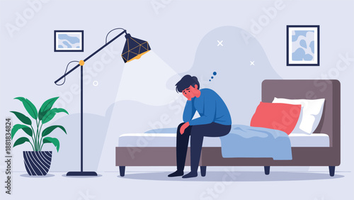 Lonely and depressed young man sitting on his bed in a dark bedroom at night feeling extremely sad and stressed.