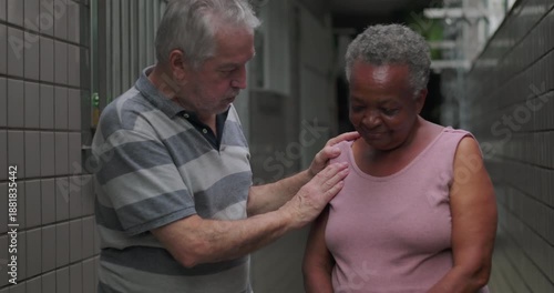 African American elderly woman held close by older man outdoors expressing protection comfort emotional safety and deep support during difficult life moment