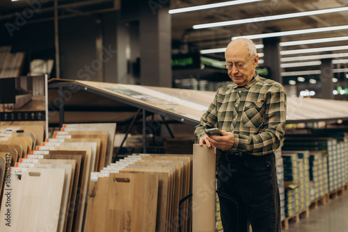 Photography Senior man using phone choosing flooring in hardware store