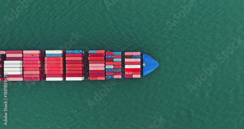 Cargo ship navigating through the open ocean, freight containers stacked on deck, illustrating global logistics, international trade, and marine transportation from a top down aerial perspective
