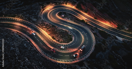 Malta: cars driving on winding night road with orange street lights, creating visually striking scene with illuminated headlights and taillights. Aerial view drone flight , top down