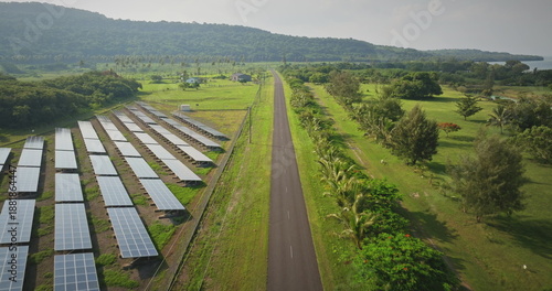 Fiji, Port Villa: solar electric panels along the road, surrounded by green fields and distant hills on Efate Island. Sustainable energy wild nature landscape. Aerial view drone flight