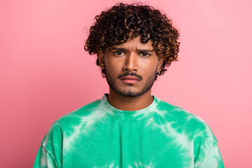 Young man in green tie dye shirt posing against pink background for fashion lifestyle image