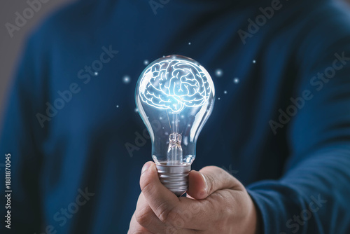 Hand holding glowing light bulb with digital human brain inside, symbol of intelligence, smart thinking, artificial intelligence, innovation knowledge for technology, education business development.